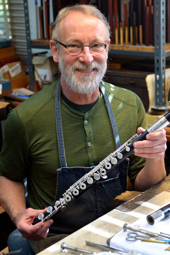 Flutemaker Chris Abell holding a wooden flute in his Grovewood Village studio.