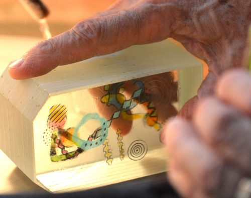 Close-up of Carl Powell's hands working on a glass sculpture in his Grovewood Village studio.