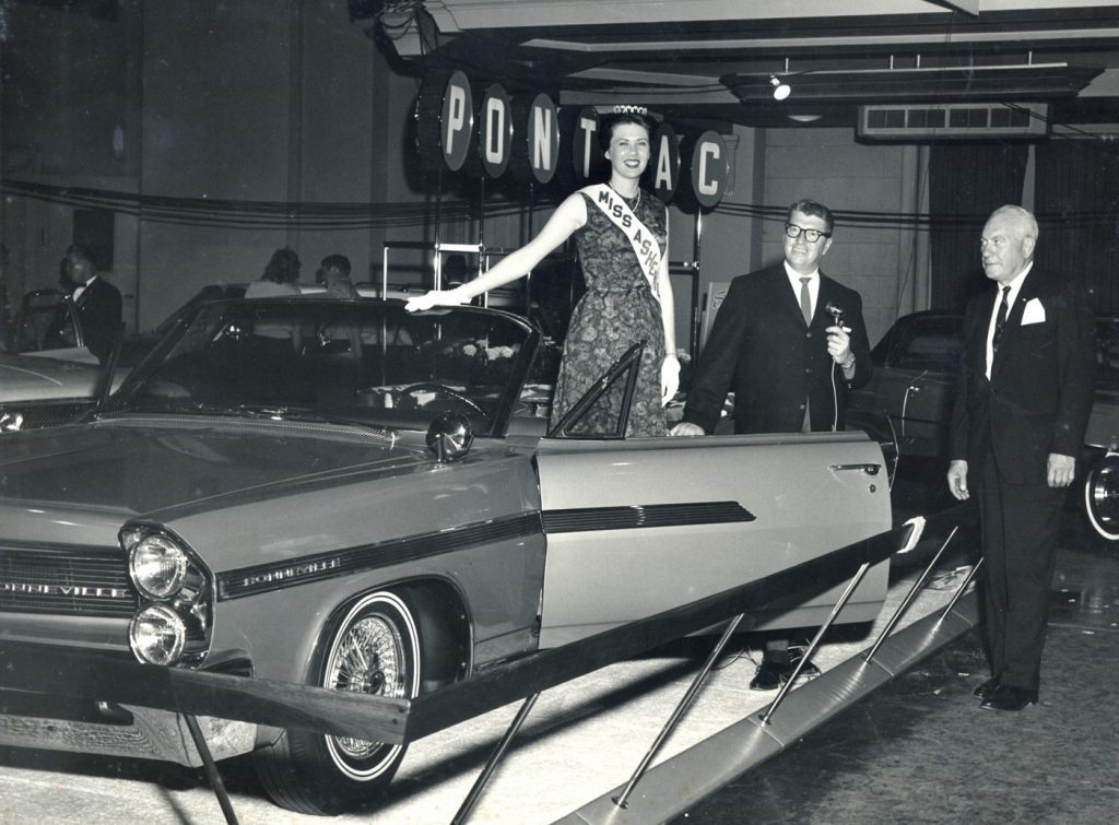 Miss Asheville and Harry Blomberg (far right) at a car show in downtown Asheville circa 1962.