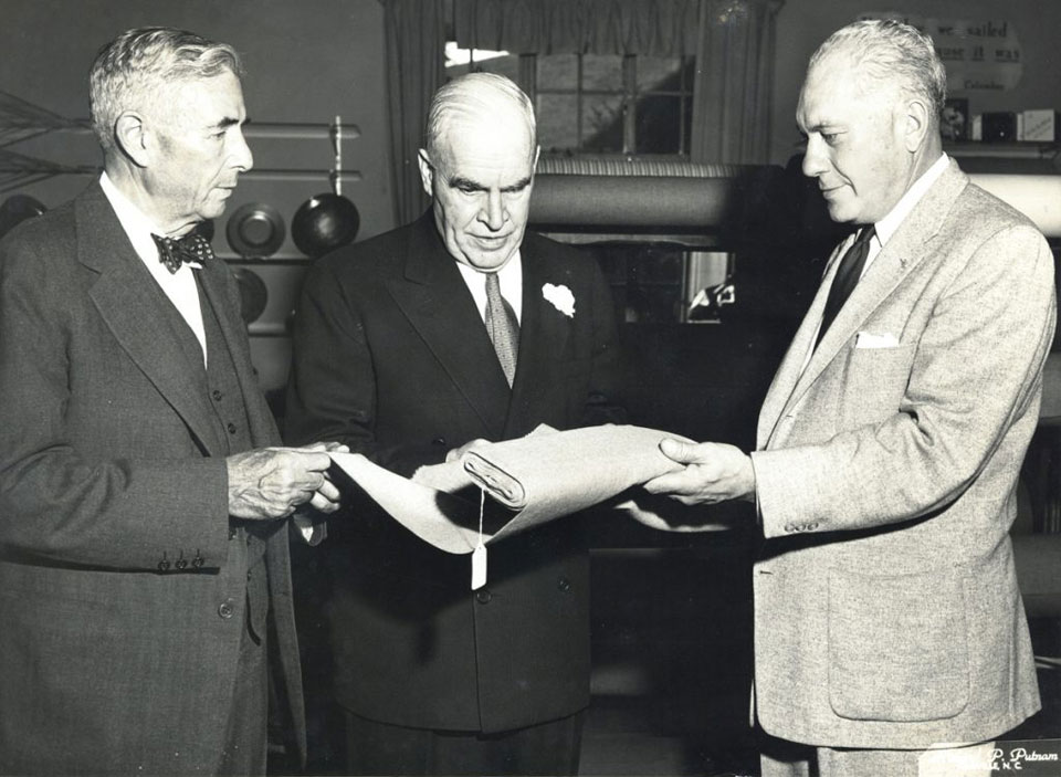 Harry Blomberg presents a bolt of Biltmore Homespun to North Carolina Governor Luther H. Hodges, circa 1953.