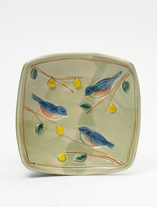 A light green ceramic square platter with a blue bird motif handmade by potter Vicki Gill.