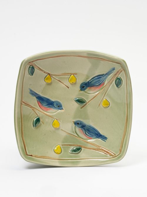 A light green ceramic square platter with a blue bird motif handmade by potter Vicki Gill.