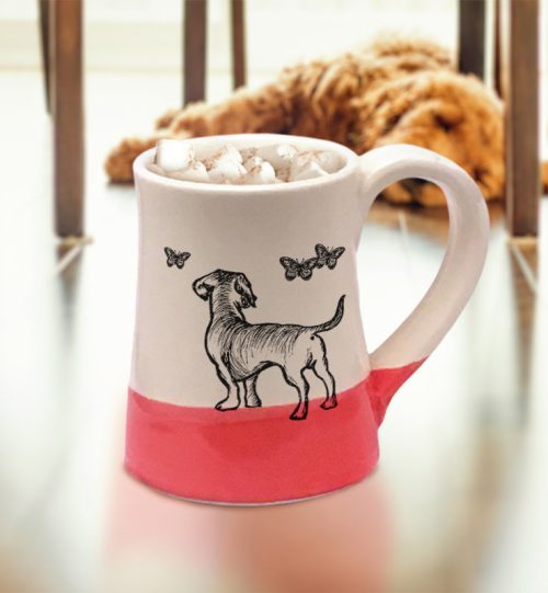 Red and white coffee mug by Darn Pottery featuring a dog chasing butterflies.