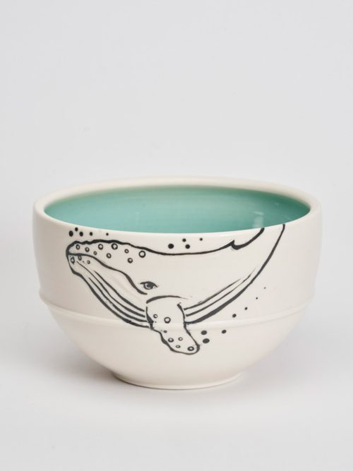 A white porcelain bowl decorated with a diving humpback whale by potter Anja Bartels.