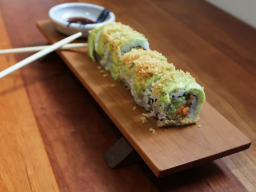 A sushi roll presented on a handmade sushi board.