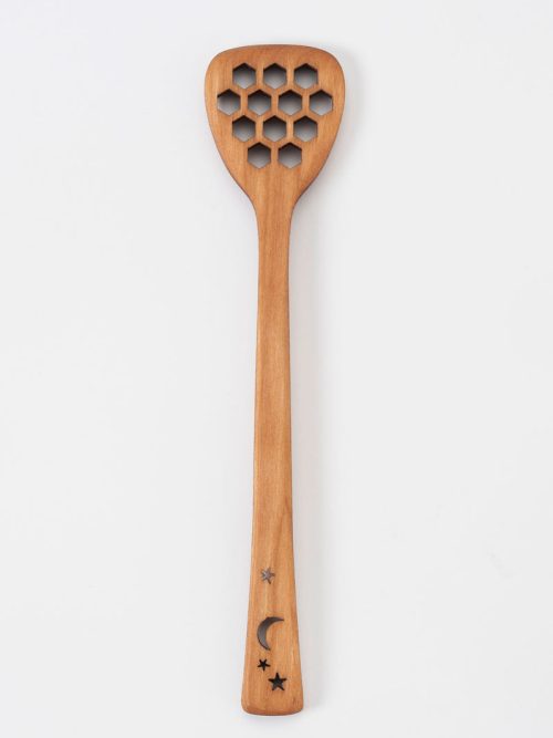 A handcrafted honey dipper with honeycomb shaped holes and a celestial motif by MoonSpoon.
