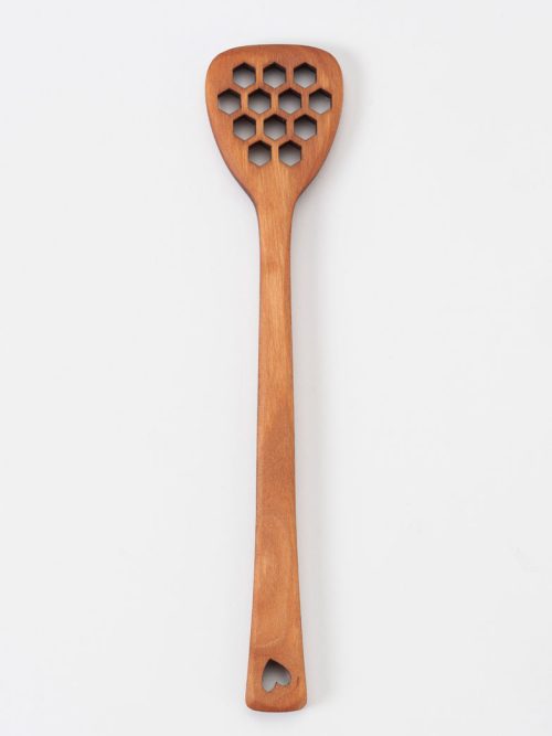 A cherry MoonSpoon honey dipper featuring honeycomb-shaped holes and a heart motif.