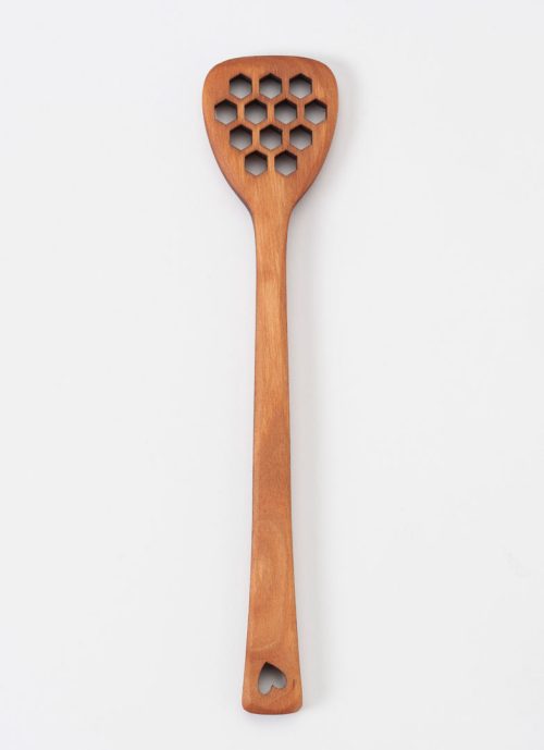 A cherry MoonSpoon honey dipper featuring honeycomb-shaped holes and a heart motif.
