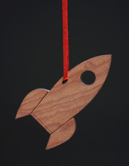 A maple rocket ornament with a red ribbon handmade by Collin Garrity.