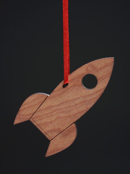 A maple rocket ornament with a red ribbon handmade by Collin Garrity.
