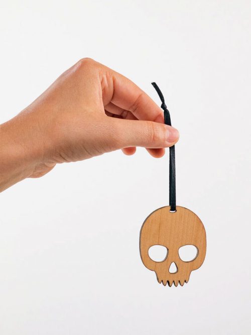 A hand holding a maple skull ornament handmade by Collin Garrity.
