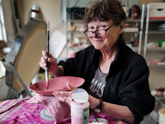 Ceramic artist Helen Purdum glazing pottery in her Grovewood Village studio.