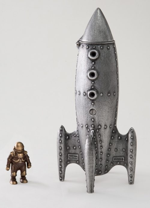 A cast aluminum and bronze sculpture by Scott Nelles of a moon rocket coin bank and spaceman.
