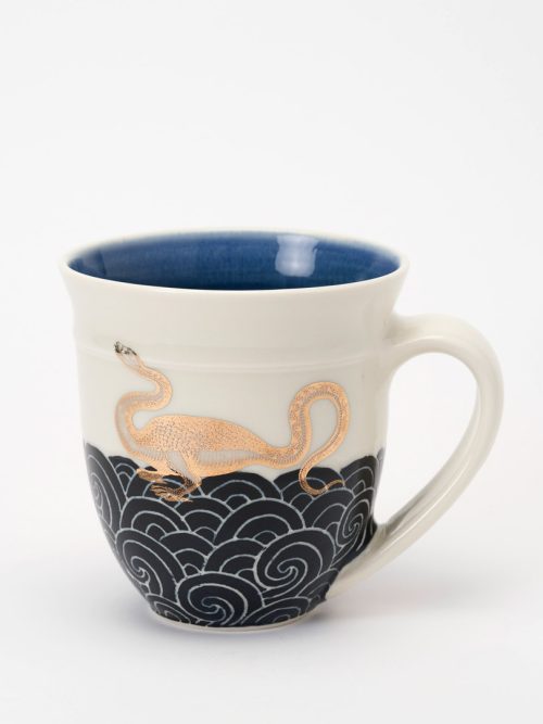 A handcrafted sea monster mug by Anja Bartels featuring dark blue waves and a gold decal.