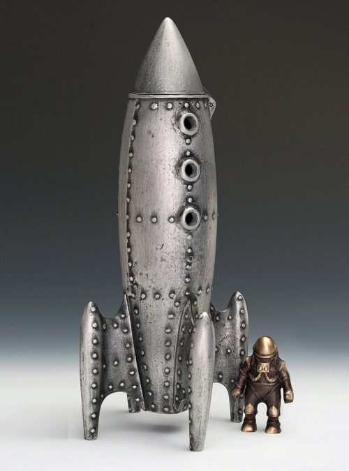 A moon rocket coin bank and spaceman handmade from cast aluminum and bronze by Scott Nelles.