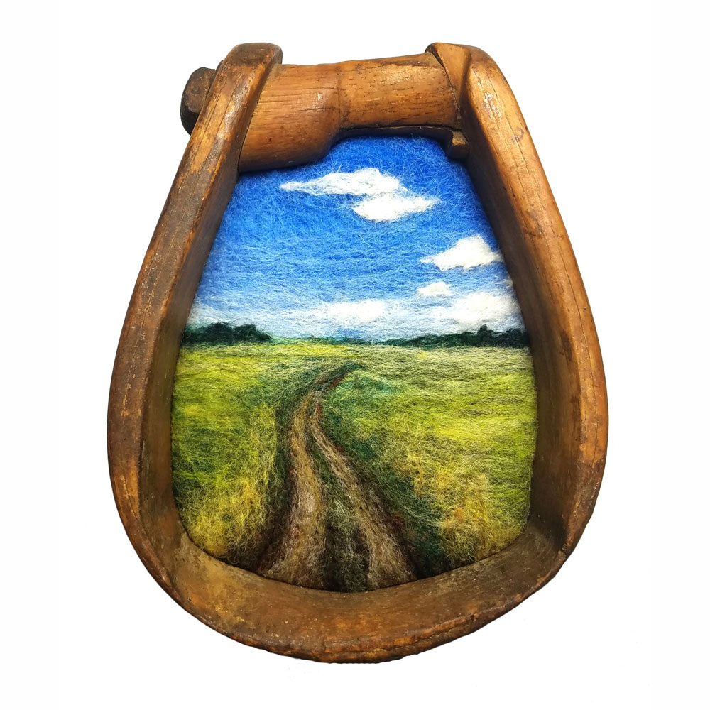 A needle-felted wool landscape in a wooden stirrup frame by Jaana Mattson.