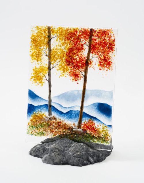 A mountain scene glass panel featuring crimson and gold trees by artist Amanda Taylor.