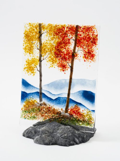 A mountain scene glass panel featuring crimson and gold trees by artist Amanda Taylor.