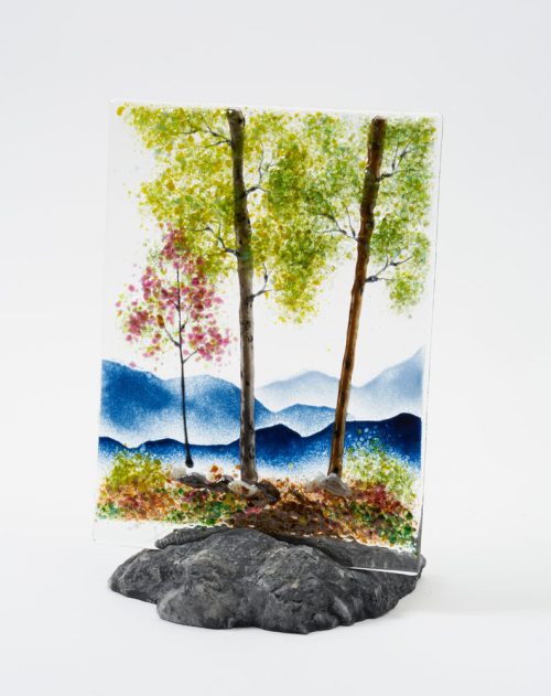 A fused glass spring mountain scene with a rock base holder by Amanda Taylor.