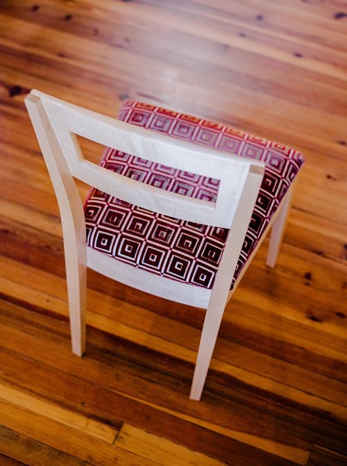 A handcrafted maple dining chair by Libby Schrum, blending mid-century lines with traditional craftsmanship and an upholstered seat for timeless comfort and style.