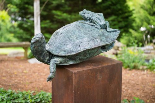 A bronze sculpture of a turtle with a frog ridning on this back by Roger Martin.