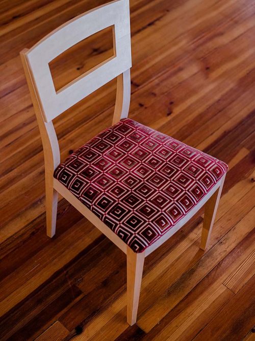A handcrafted maple dining chair by Libby Schrum, blending mid-century lines with traditional craftsmanship and an upholstered seat for timeless comfort and style.