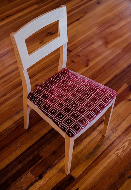 A handcrafted maple dining chair by Libby Schrum, blending mid-century lines with traditional craftsmanship and an upholstered seat for timeless comfort and style.