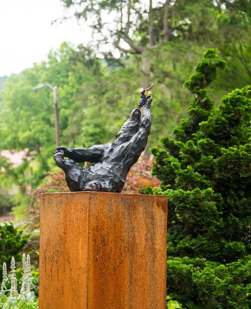 An outdoor sculpture of a bear eating grapes titled Bacchus by artist Roger Martin.