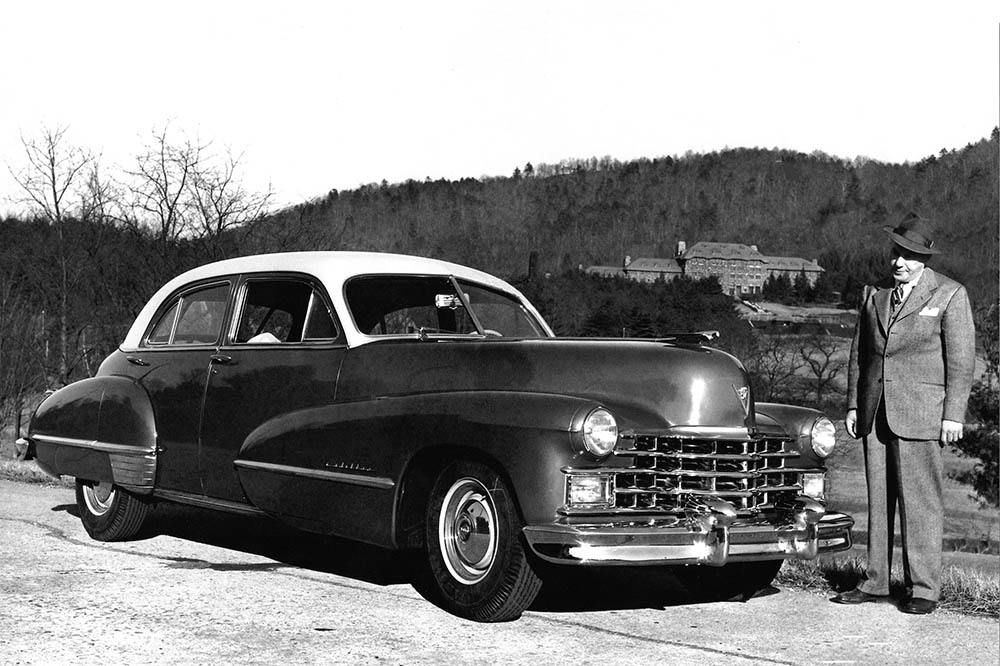 Harry Blomberg stands beside a Cadillac, with the Grove Park Inn in the background (c. 1947).