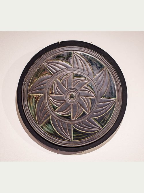 A pewter and green circular wll piece by Leslie Green Guilbault.